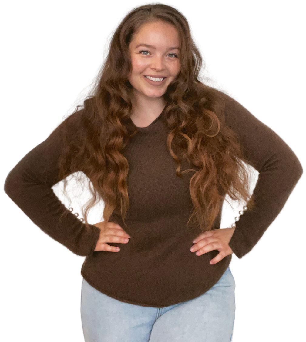 Zenia Radoor, smiling with hands on hips, used next to an introductory text on the homepage, introducing herself as a perfectionist in progress, aspiring author, and bookworm extraordinaire.